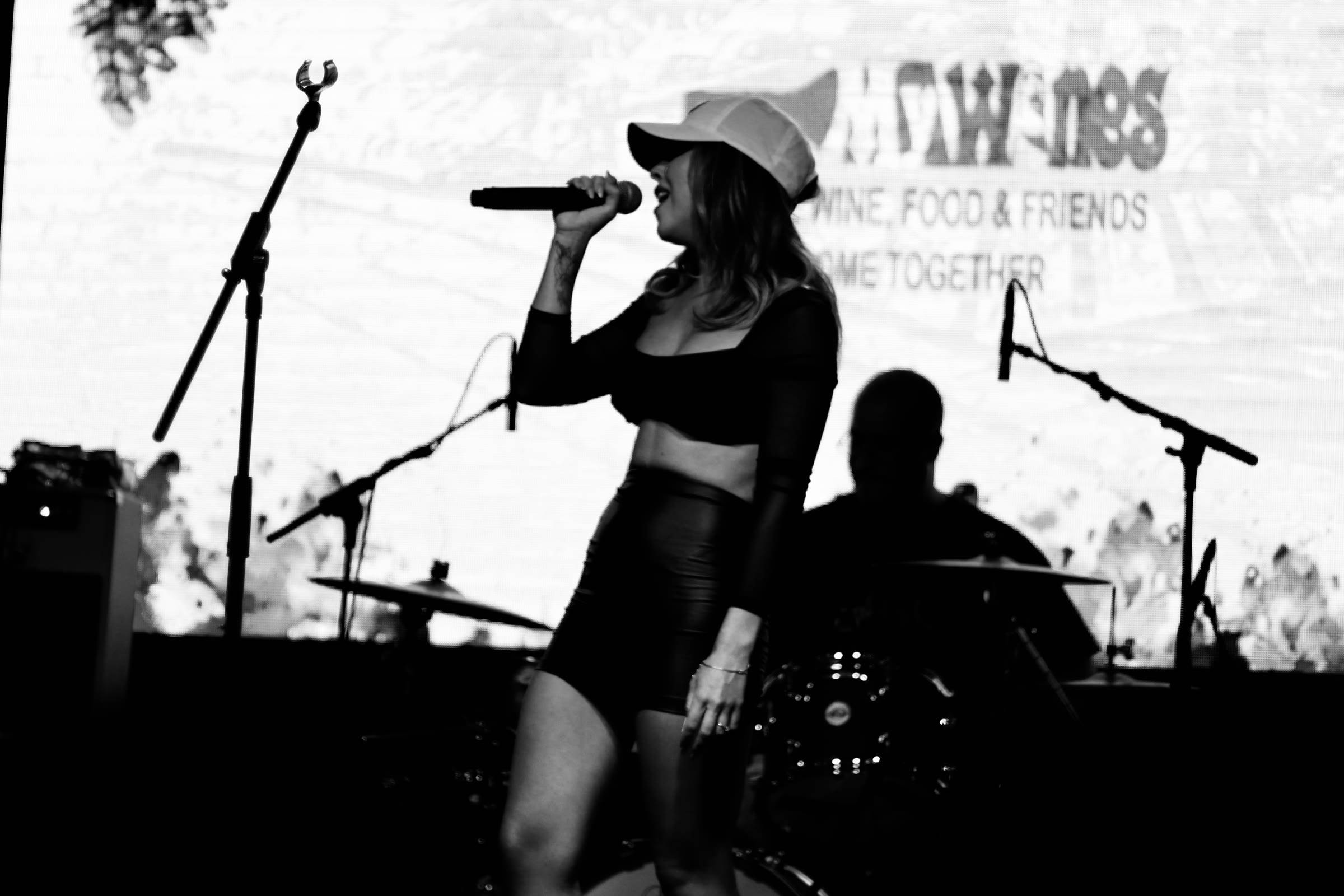 A singer silhouetted against a festival screen, in black and white
