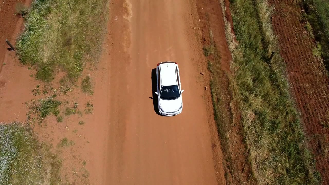 A car on a red dirt road in Western Australia, from a drone