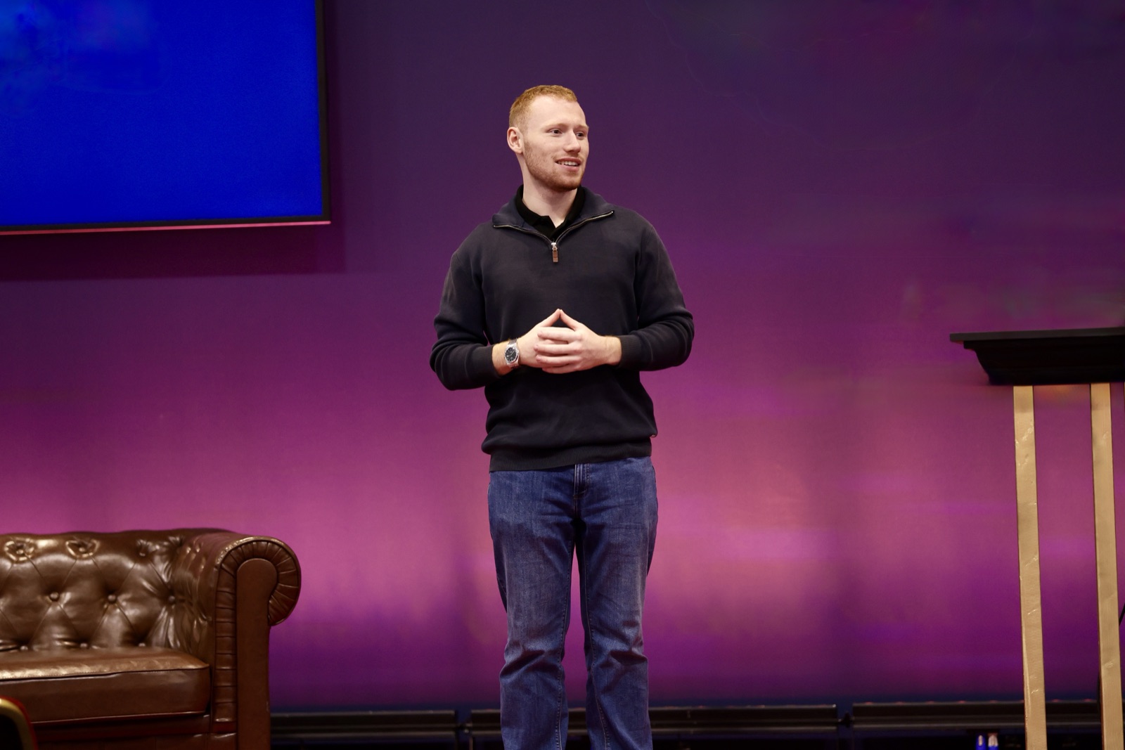 Joseph Carey on stage in front of a purple wall