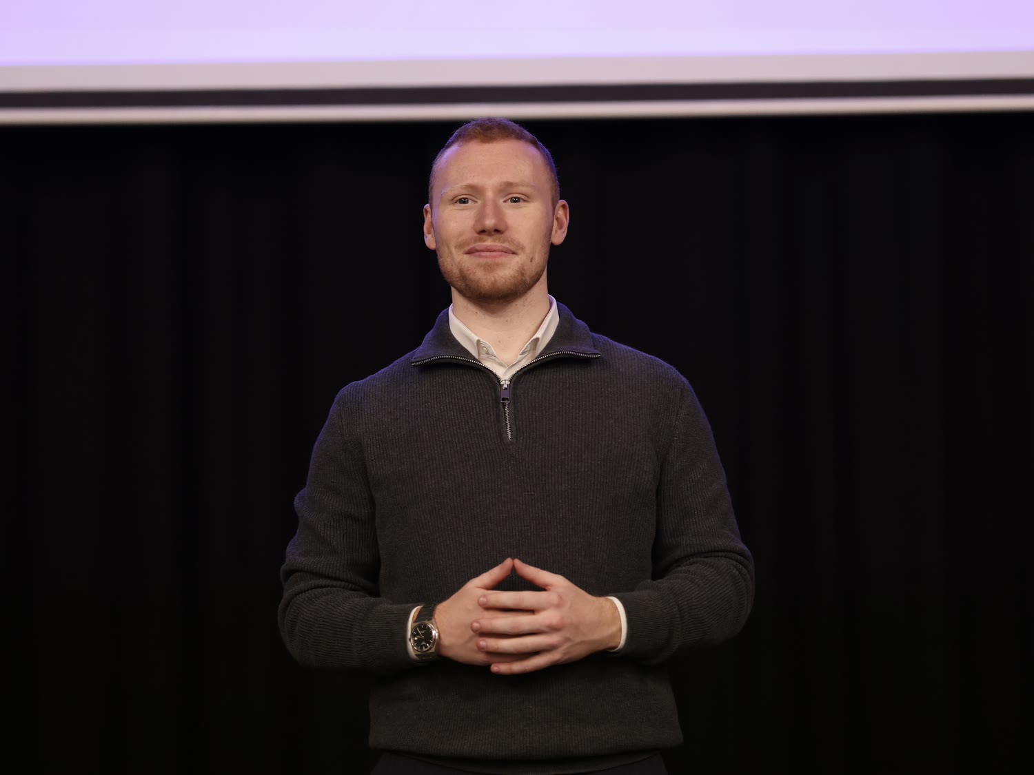 Joseph Carey speaking on a conference stage in Milton Keynes